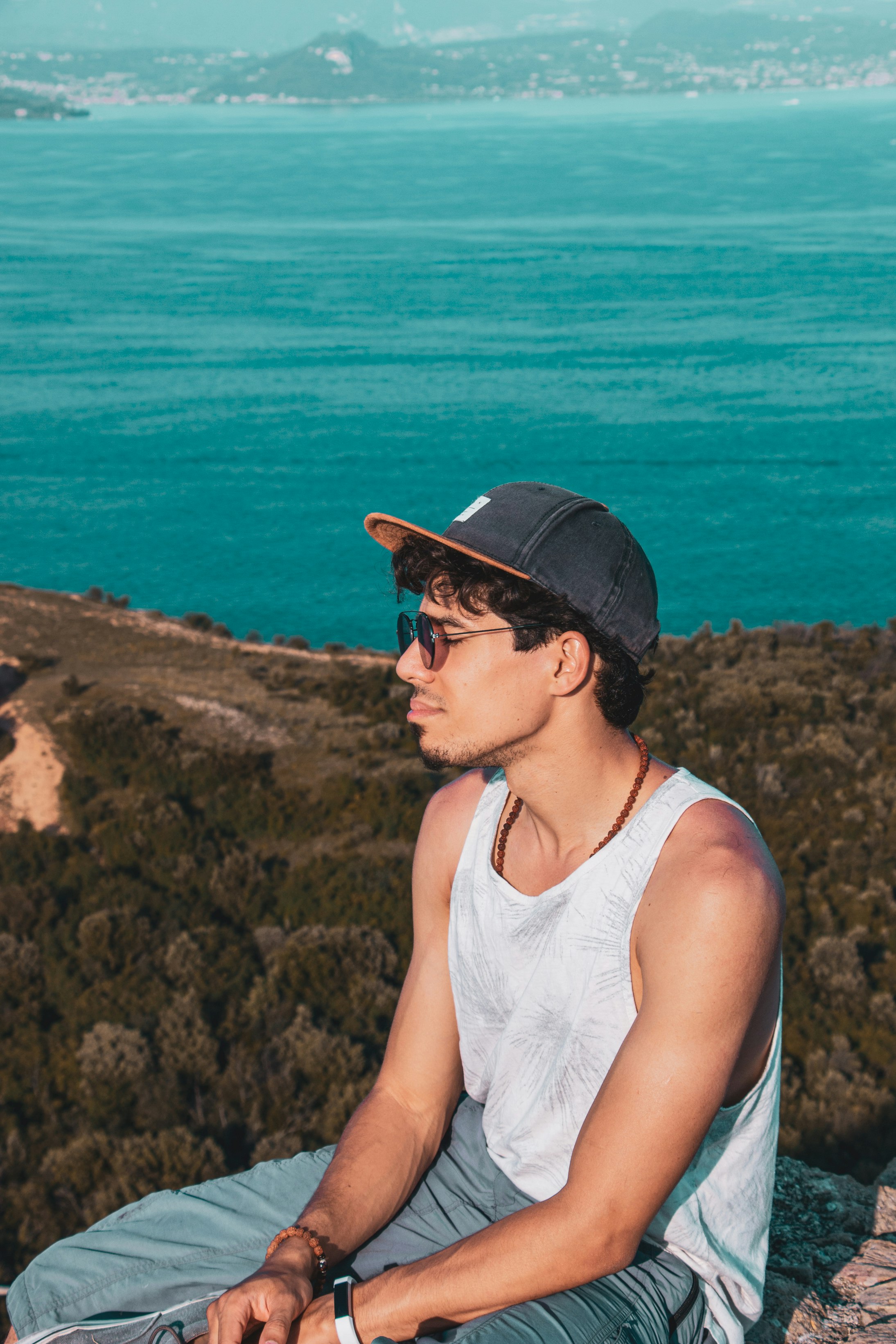 woman in white tank top wearing brown fedora hat standing on brown rock formation near blue